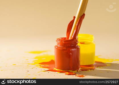 Close-up of a paintbrush dipped into a bottle of red paint