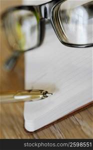 Close-up of a pair of eyeglasses with a pen and a diary