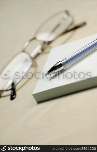 Close-up of a pair of eyeglasses with a pen and adhesive notes