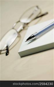 Close-up of a pair of eyeglasses with a pen and adhesive notes
