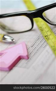 Close-up of a pair of eyeglasses with a tape measure and a pen on a document