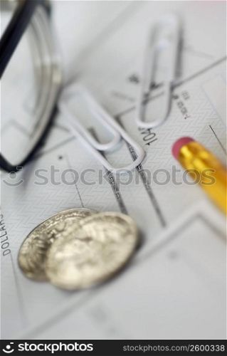 Close-up of a pair of eyeglasses with paper clips and coins on a check