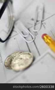 Close-up of a pair of eyeglasses with paper clips and coins on a check