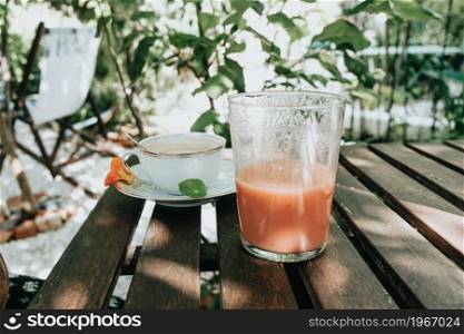 Close up of a pair of fresh summer drinks over a wooden table during a sunny day, refreshing drink