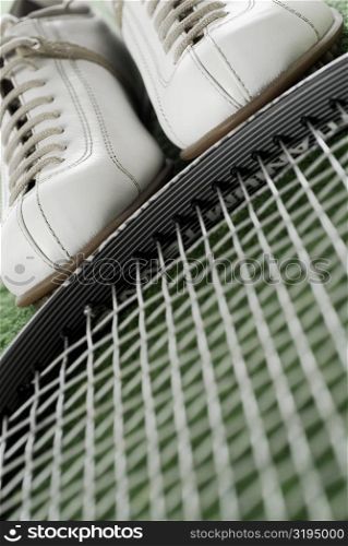 Close-up of a pair of sports shoes and a tennis racket
