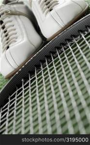 Close-up of a pair of sports shoes and a tennis racket