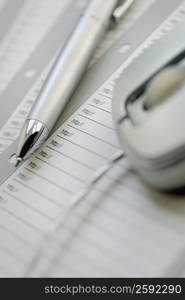 Close-up of a pen and a computer mouse on a sheet of paper