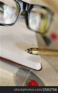Close-up of a pen and a pair of eyeglasses on a dairy