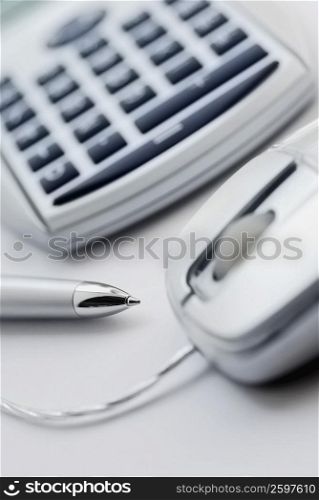 Close-up of a pen and computer mouse with a calculator