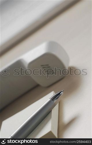 Close-up of a pen on a diary with a telephone receiver