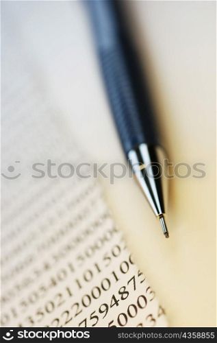 Close-up of a pen with a torn financial page