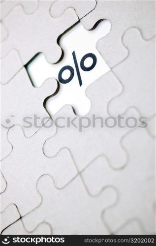 Close-up of a percentage sign and a jigsaw puzzle