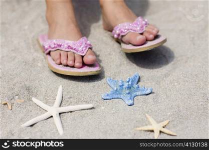 Close-up of a person&acute;s feet on the beach near three starfish