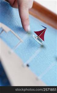 Close-up of a person&acute;s finger pointing to an architectural model of a sailboat