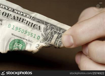 Close-up of a person&acute;s fingers holding a burnt American dollar bill