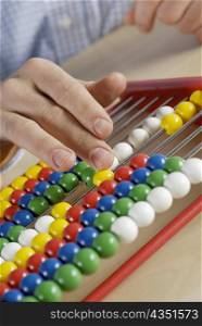 Close-up of a person&acute;s hand counting beads on an abacus