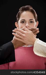 Close-up of a person&acute;s hand covering a businesswoman&acute;s mouth