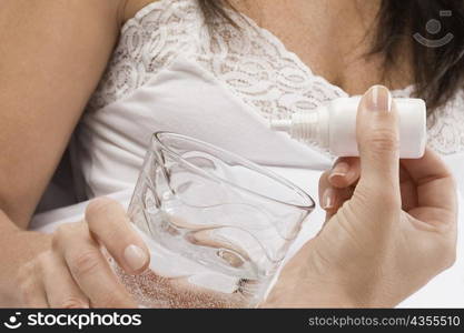 Close-up of a person&acute;s hand dropping medicine into a glass of water