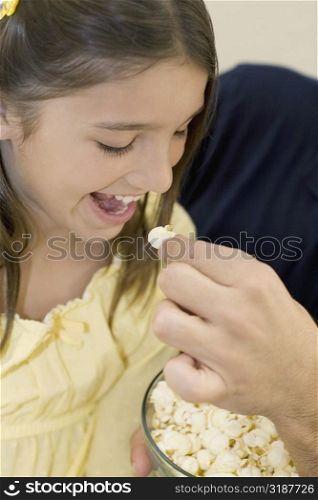 Close-up of a person&acute;s hand feeding popcorn to a girl