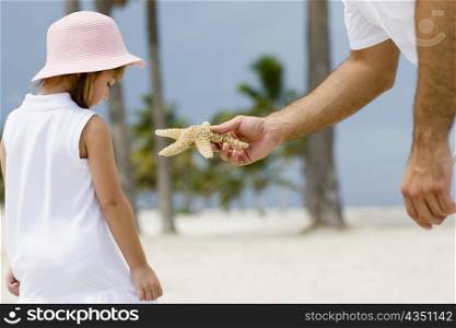 Close-up of a person&acute;s hand giving a starfish to a girl