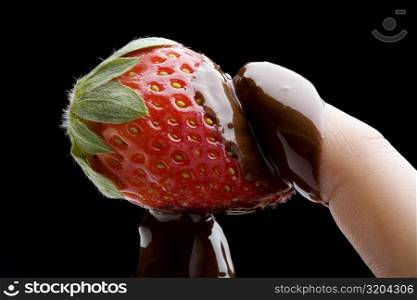 Close-up of a person&acute;s hand holding a chocolate covered strawberry