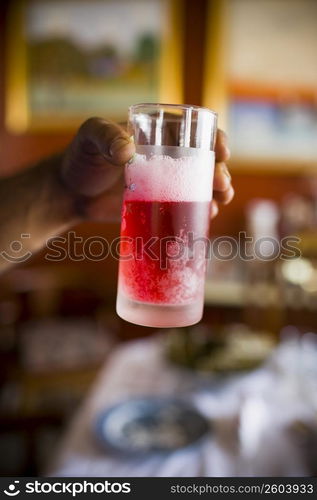 Close-up of a person&acute;s hand holding a glass of strawberry juice