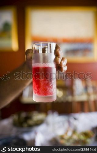 Close-up of a person&acute;s hand holding a glass of strawberry juice