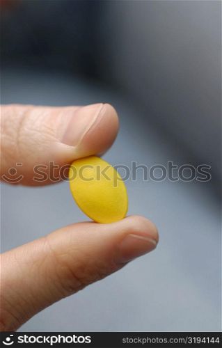 Close-up of a person&acute;s hand holding a pill