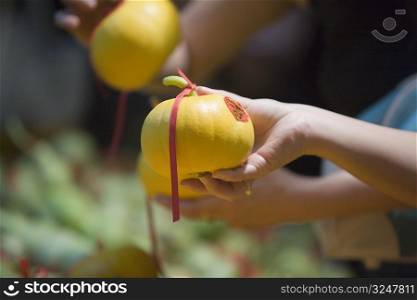 Close-up of a person&acute;s hand holding a pomelo tied up with a ribbon