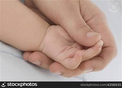 Close-up of a person&acute;s hand holding baby&acute;s hand
