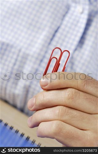Close-up of a person&acute;s hand holding two paper clips