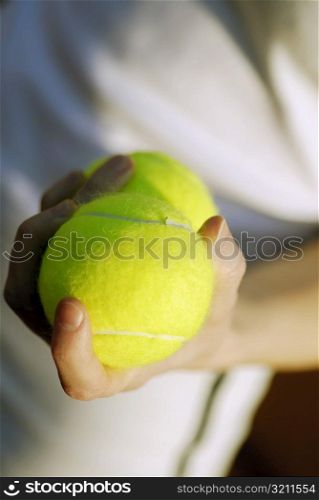 Close-up of a person&acute;s hand holding two tennis balls