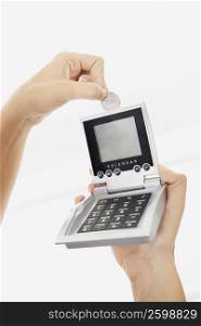 Close-up of a person&acute;s hand inserting a coin into a calculator
