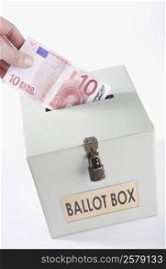 Close-up of a person&acute;s hand inserting ten euro banknote into a ballot box