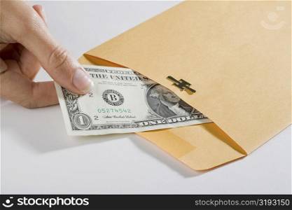 Close-up of a person&acute;s hand picking out a US dollar bill from an envelope