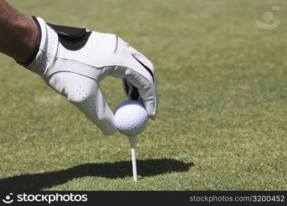 Close-up of a person&acute;s hand positioning a golf ball on a golf tee