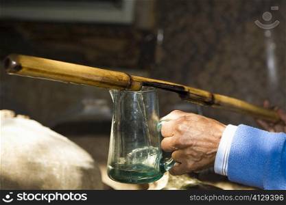 Close-up of a person&acute;s hand pouring pisco in a glass from a bamboo stick, Ica, Ica Region, Peru