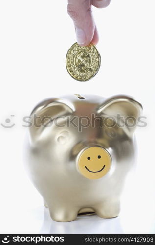 Close-up of a person&acute;s hand putting a coin into a piggy bank