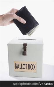 Close-up of a person&acute;s hand putting money full of wallet into a ballot box