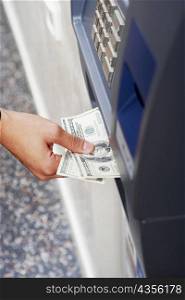 Close-up of a person&acute;s hand receiving one hundred dollar bills from an ATM
