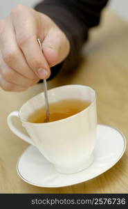 Close-up of a person&acute;s hand stirring tea with a teaspoon