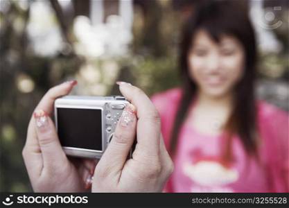 Close-up of a person&acute;s hand taking a photograph of a young woman smiling