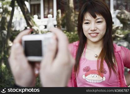 Close-up of a person&acute;s hand taking a photograph of a young woman smiling
