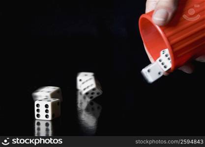 Close-up of a person&acute;s hand throwing dice from a cup