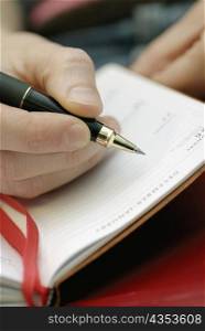 Close-up of a person&acute;s hand writing in a diary