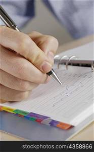 Close-up of a person&acute;s hand writing on a spiral notebook
