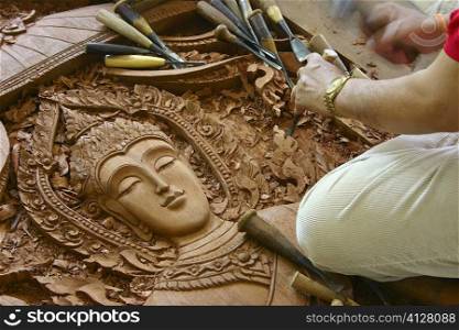 Close-up of a person&acute;s hands carving a statue of Buddha on wood, Chiang Rai, Thailand