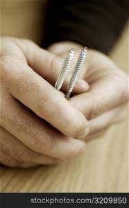 Close-up of a person&acute;s hands holding two screws