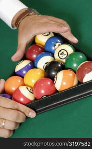 Close-up of a person&acute;s hands racking up pool balls on a pool table