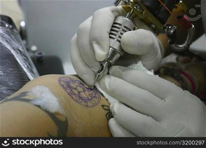 Close-up of a person&acute;s hands tattooing on a person&acute;s arm, Bangkok, Thailand